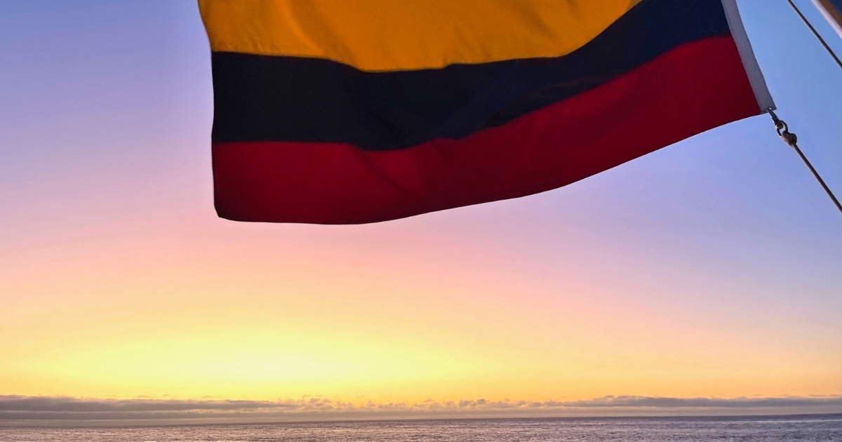 Close up of the Ecuador flag flying in the breeze over the water at sunset